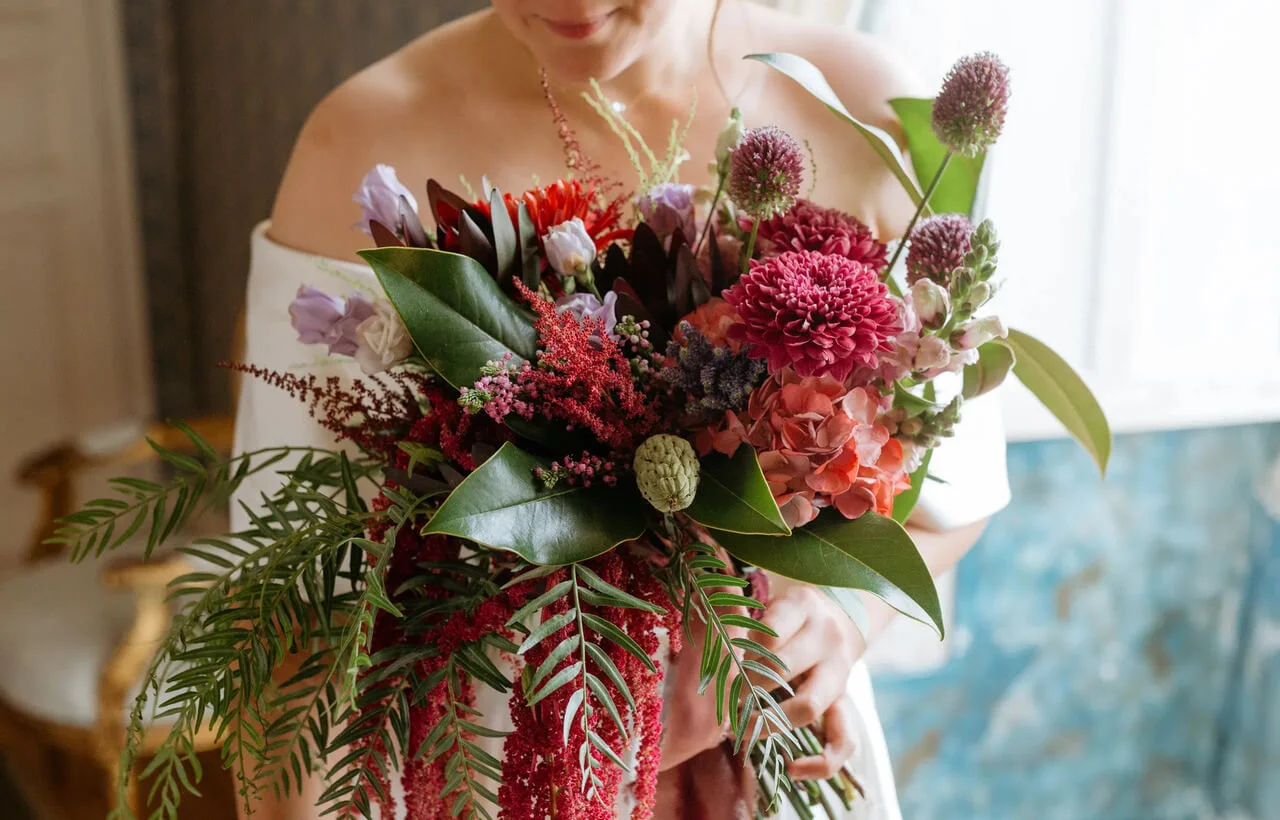 A bride holds a large, very colorful wedding bouquet