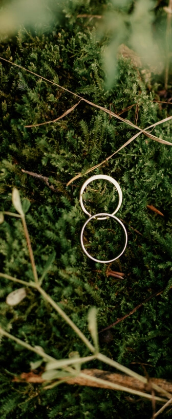 Des alliances sont posées sur la mousse pour la cérémonie intimiste de l’elopement. Crédit photo : Sophie Bachère
