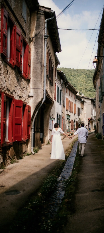 Des mariés se promènent dans un village pittoresque d’Occitanie lors d’un elopement en Occitanie. Crédit photo : Sophie Bachère