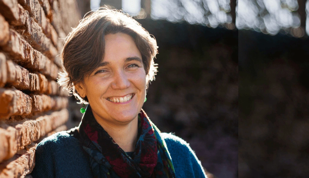 Delphine Goudy, wedding planner de Toulouse, sourit à côté d’un mur de briques. Crédit photo : Sophie Bachère